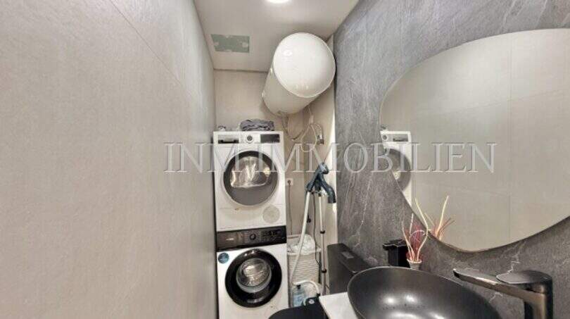 Modernes Badezimmer mit grauem Waschbecken, Spiegel und Waschmaschine in Maisonette-Wohnung Porto Cristo