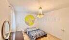 Helles Schlafzimmer der Stranwohnung in El Arenal mit Doppelbett, Kristallleuchter und rundem Wandbild.