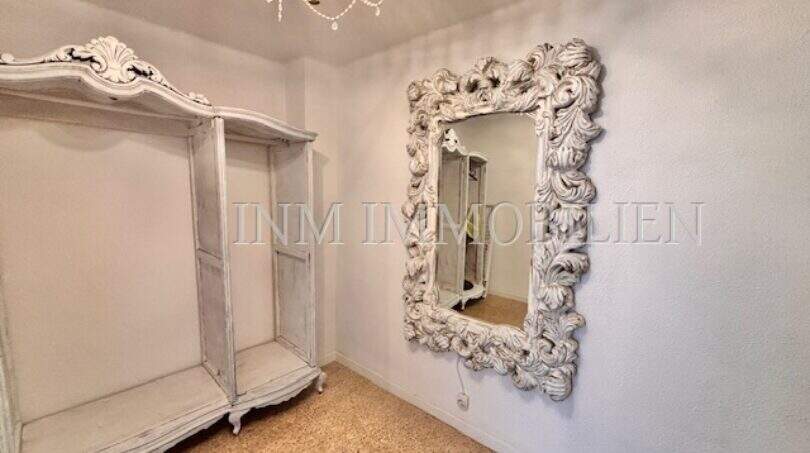 Helles Zimmer der Strandwohnung in El Arenal mit verziertem Barockspiegel, weißem Regal und Kronleuchter.