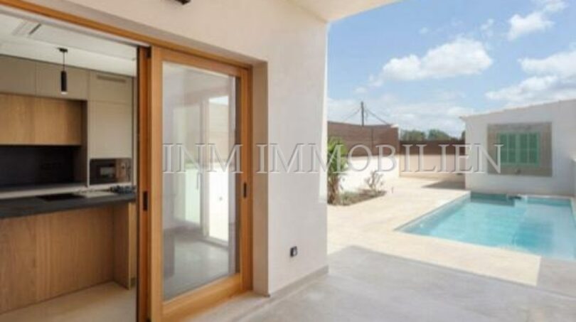 Covered terrace with pool view and modern kitchen area with wooden sliding door in new build village house Biniali