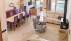 Open living-dining area with purple chairs, fireplace and pool view in luxury new build in Biniali