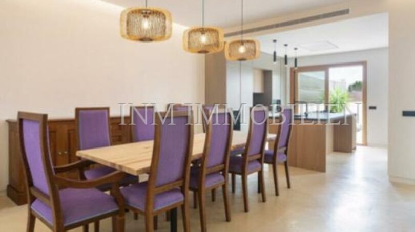 Elegant dining room with purple chairs, wooden table and pendant lights in luxury new build in Biniali