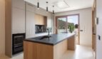 Modern fitted kitchen with kitchen island, wooden fronts and dark worktop in luxury new build in Biniali