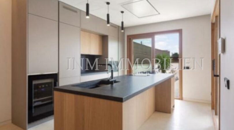 Modern fitted kitchen with kitchen island, wooden fronts and dark worktop in luxury new build in Biniali