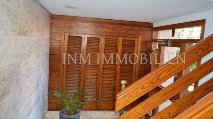 Entrance area with wooden paneling, louvered doors and marble walls in designer apartment in Palma de Mallorca.