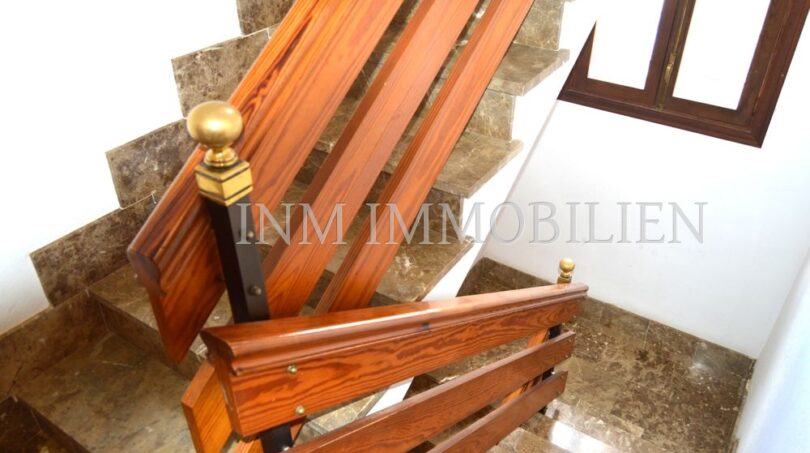Elegant staircase with wooden railing and brass knob on marble steps in fully renovated apartment, Palma