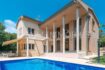 Außenansicht der Villa in Calvià mit großem Pool, Terrasse, Säulenveranda und mediterranem Garten.