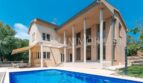 Exterior view of the villa in Calvià with large pool, terrace, columned veranda and Mediterranean garden.