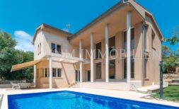 Außenansicht der Villa in Calvià mit großem Pool, Terrasse, Säulenveranda und mediterranem Garten.