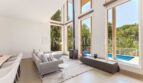 Bright living room with panoramic windows, fireplace and pool view of the villa in Cala Vinyes
