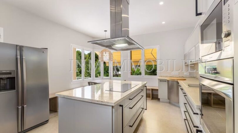 Modern kitchen of the villa in Cala Vinyes with kitchen island, granite countertops and stainless steel appliances