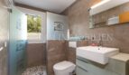 Modern bathroom of the villa in Cala Vinyes with shower, toilet and sink, brown natural stone look tiles