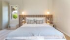 Bright bedroom of the villa in Cala Vinyes with double bed, wooden headboard and elegant pendant lights