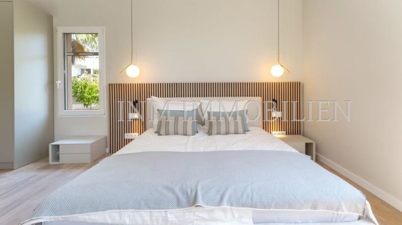 Bright bedroom of the villa in Cala Vinyes with double bed, wooden headboard and elegant pendant lights