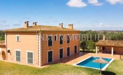 Exterior view of a large finca in Santanyí with pool, lawn and wide view of the countryside.
