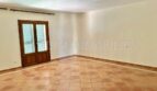 Luminosa sala de estar vacía con azulejos de terracota y puerta doble a la terraza en la finca Santanyí