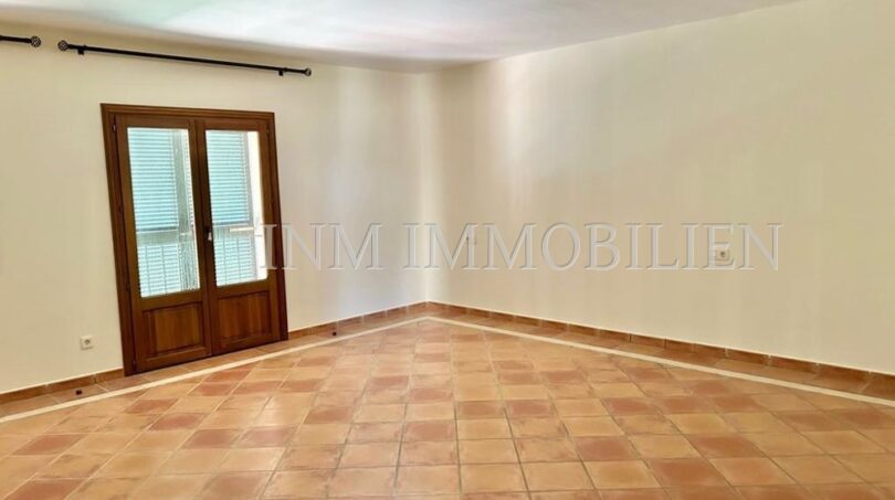 Luminosa sala de estar vacía con azulejos de terracota y puerta doble a la terraza en la finca Santanyí