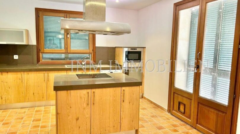 Cocina empotrada moderna con isla de cocina, campana extractora y suelo de terracota en la finca Santanyí