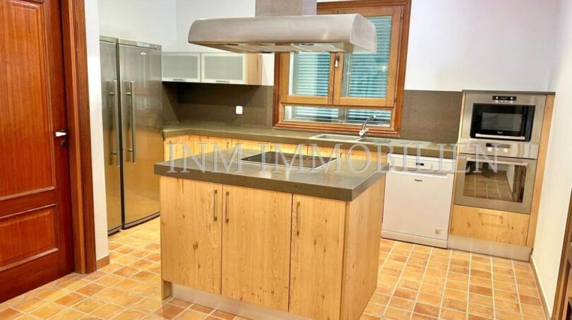 Cocina empotrada moderna con isla de cocina, electrodomésticos de acero inoxidable y suelo de terracota en la finca Santanyí