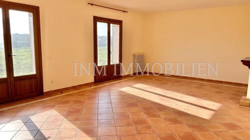 Luminosa sala de estar de la finca en Santanyí con suelo de terracota, dos puertas de madera y radiador