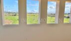 Habitación luminosa con cuatro grandes ventanas, vista a campos verdes y pueblo de Santanyí, finca Mallorca