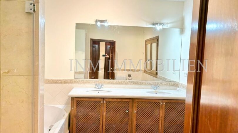 Elegante baño de la finca en Santanyí con lavabo doble, mueble de madera y espejo grande
