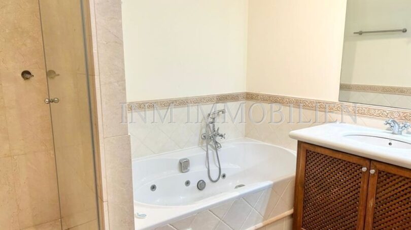 Baño de la finca en Santanyí con bañera de hidromasaje, ducha de cristal y mueble de madera