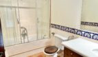 Baño de la finca Santanyí con bañera, ducha, lavamanos de madera y azulejos azules decorativos