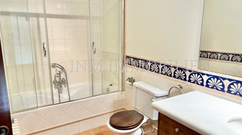 Baño de la finca Santanyí con bañera, ducha, lavamanos de madera y azulejos azules decorativos