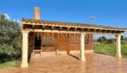 Terraza cubierta con zona de barbacoa y pilares de piedra natural de la finca en Santanyí