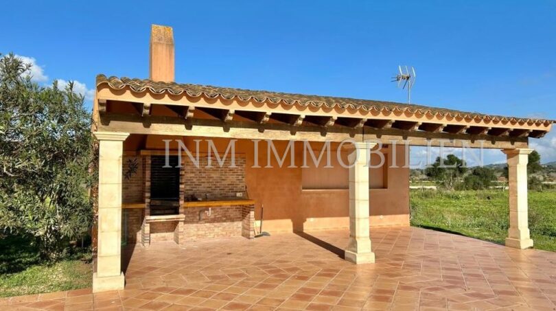 Terraza cubierta con zona de barbacoa y pilares de piedra natural de la finca en Santanyí