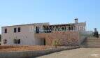 Exterior view of a high-quality finca in Campos with natural stone wall, white façade, terrace and external stairs.