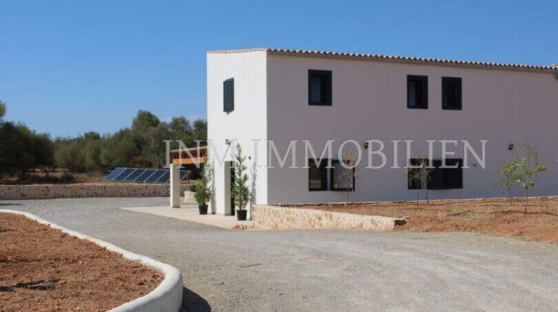 Exterior view of a modern finca in Campos with gravel driveway, terracotta roof, shutters and solar system.