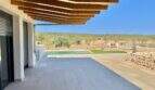 Covered terrace with wooden beams, pool and panoramic view of fields and hills of the finca in Campos.