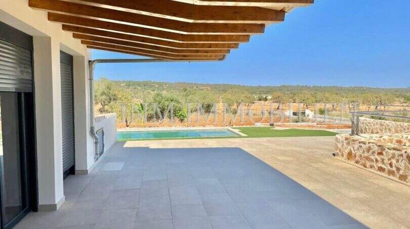 Covered terrace with wooden beams, pool and panoramic view of fields and hills of the finca in Campos.