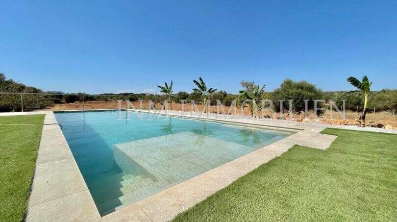 Large outdoor pool with stepped entry, well-maintained lawn and panoramic view of the landscape of the finca in Campos.