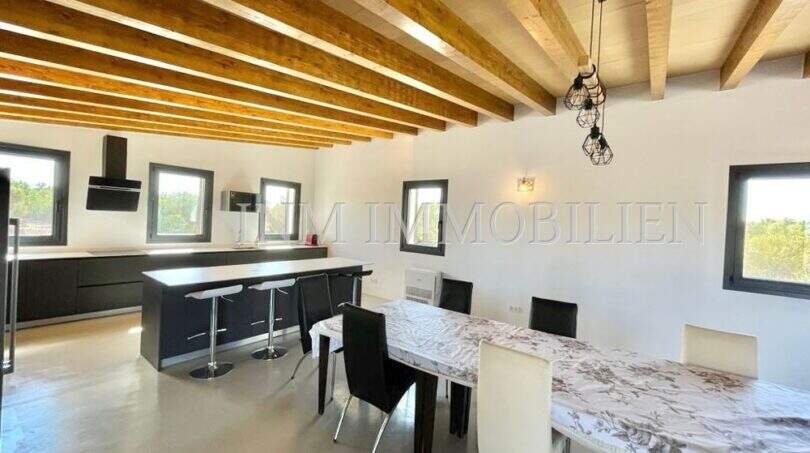 Open kitchen with dining area, wooden beam ceiling and modern fittings in high-quality finca in Campos