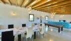 Spacious living room of the Campos finca with wooden beam ceiling, dining table, pool table and turquoise sofa.