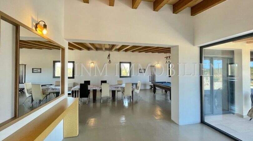 Open living-dining area with wooden beam ceiling, pool table and large glass front in high-quality finca, Campos