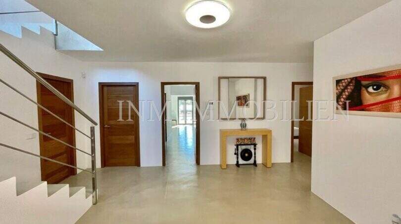 Bright entrance area of the finca in Campos with modern staircase, wooden doors and elegant concrete flooring.
