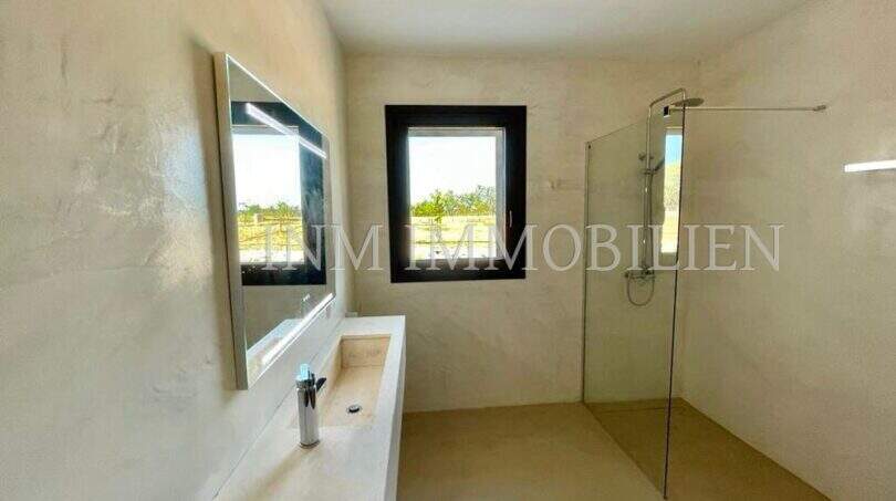 Modern bathroom of the Campos finca with walk-in shower, integrated sink and natural stone design