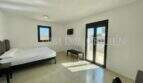 Bright bedroom of the Campos finca with double bed, TV, terrace access and modern concrete flooring.