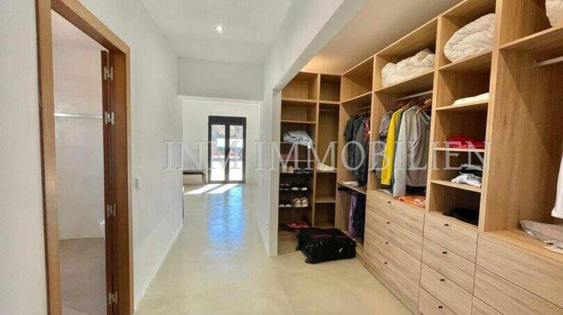 Spacious dressing room with light wood cabinets, open shelves and drawers in high-quality finca in Campos