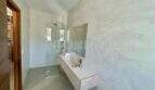 Modern bathroom of the Campos finca with walk-in shower, elegant natural stone sink and atmospheric wall design.