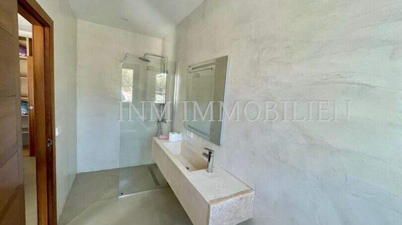 Modern bathroom of the Campos finca with walk-in shower, elegant natural stone sink and atmospheric wall design.