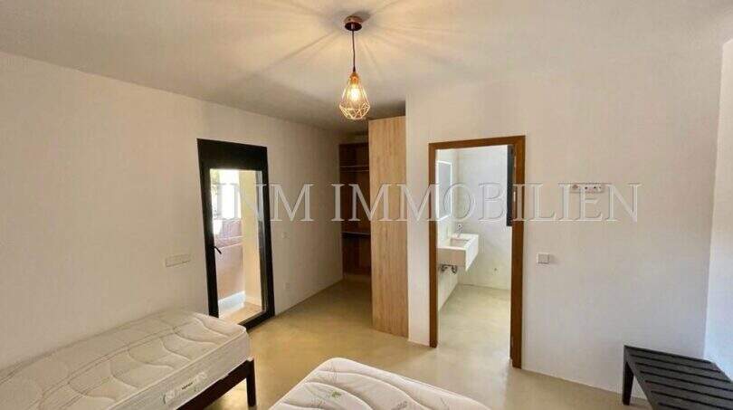 Bedroom of the Campos finca with two single beds, pendant light, built-in wardrobe and adjoining bathroom