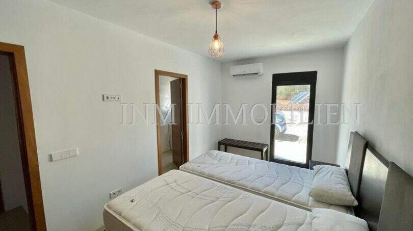 Bedroom of the Campos finca with two single beds, air conditioning, pendant light and access to outdoor area