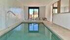 Modern indoor pool of the finca in Campos with water inlet, panoramic windows and mirror wall