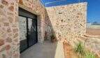 Terrace of the Campos finca with natural stone walls, modern sliding doors and roof terrace with stainless steel railing