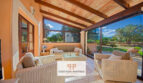 Terraza cubierta de la finca Felanitx con muebles de ratán, techo de vigas de madera y vistas al jardín verde